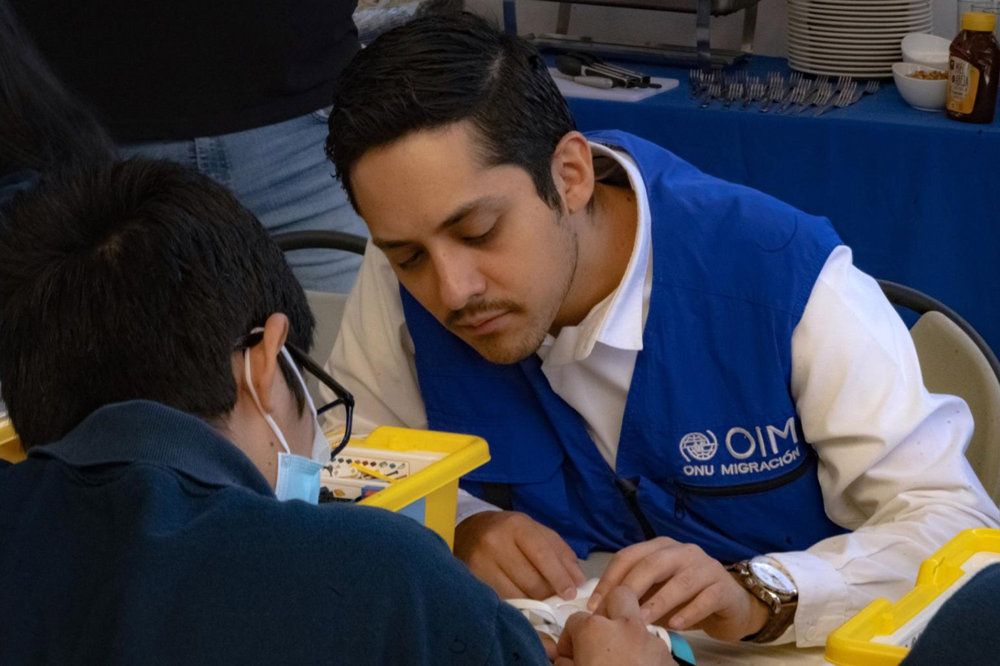 Dr. Jürgen Adam Sánchez, Youth changemaker with OIM Mexico, and another persona seated at a table, actively engaged in an activity.