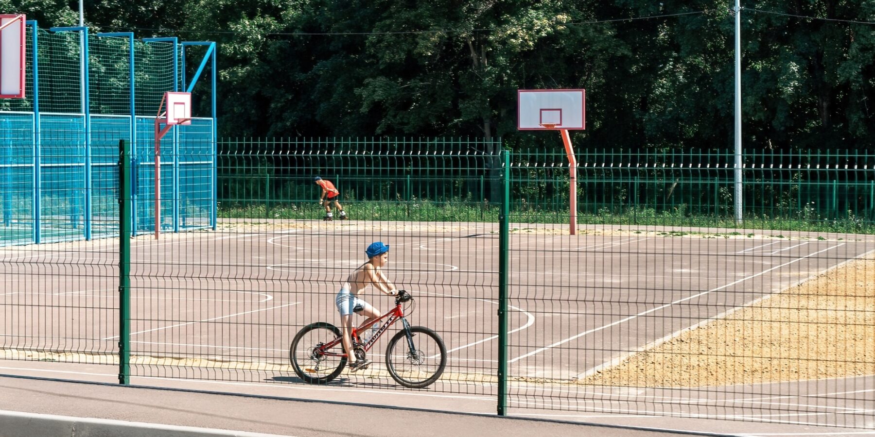 A school playground in Kharkiv with a kid biking and another one skating.