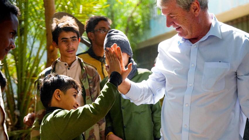Peter sharing a high five with a boy and a few people are standing around them