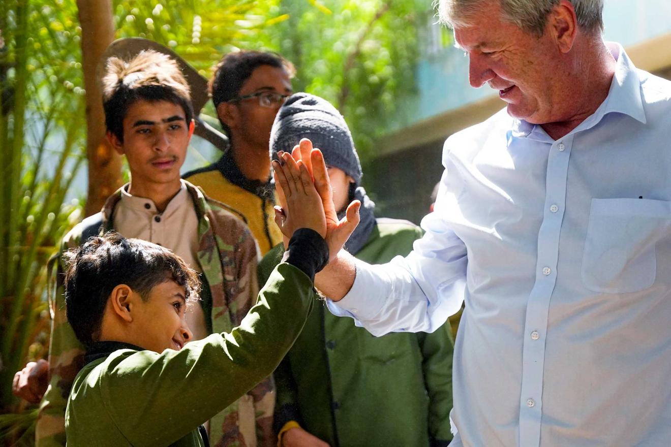 Peter sharing a high five with a boy and a few people are standing around them