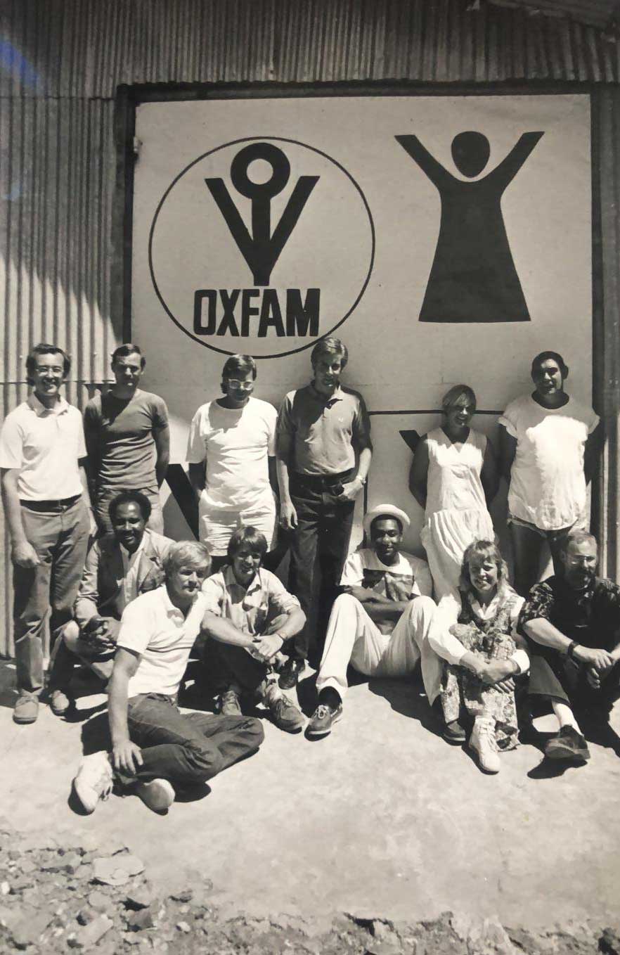 Vintage photo of a group of people with oxfam logo in the background