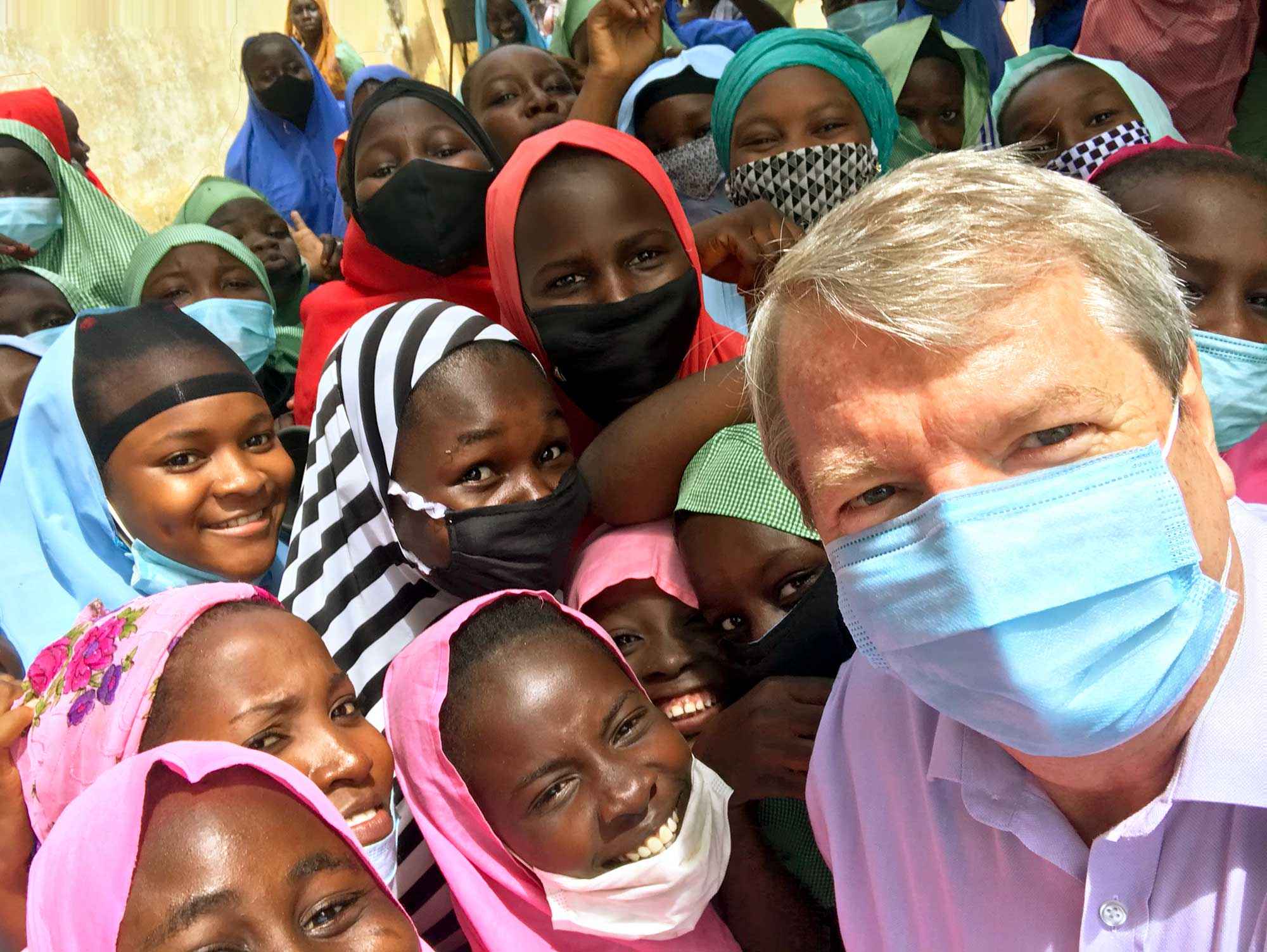 Peter taking photo with a group of girls wearing veils and some wearing covid masks