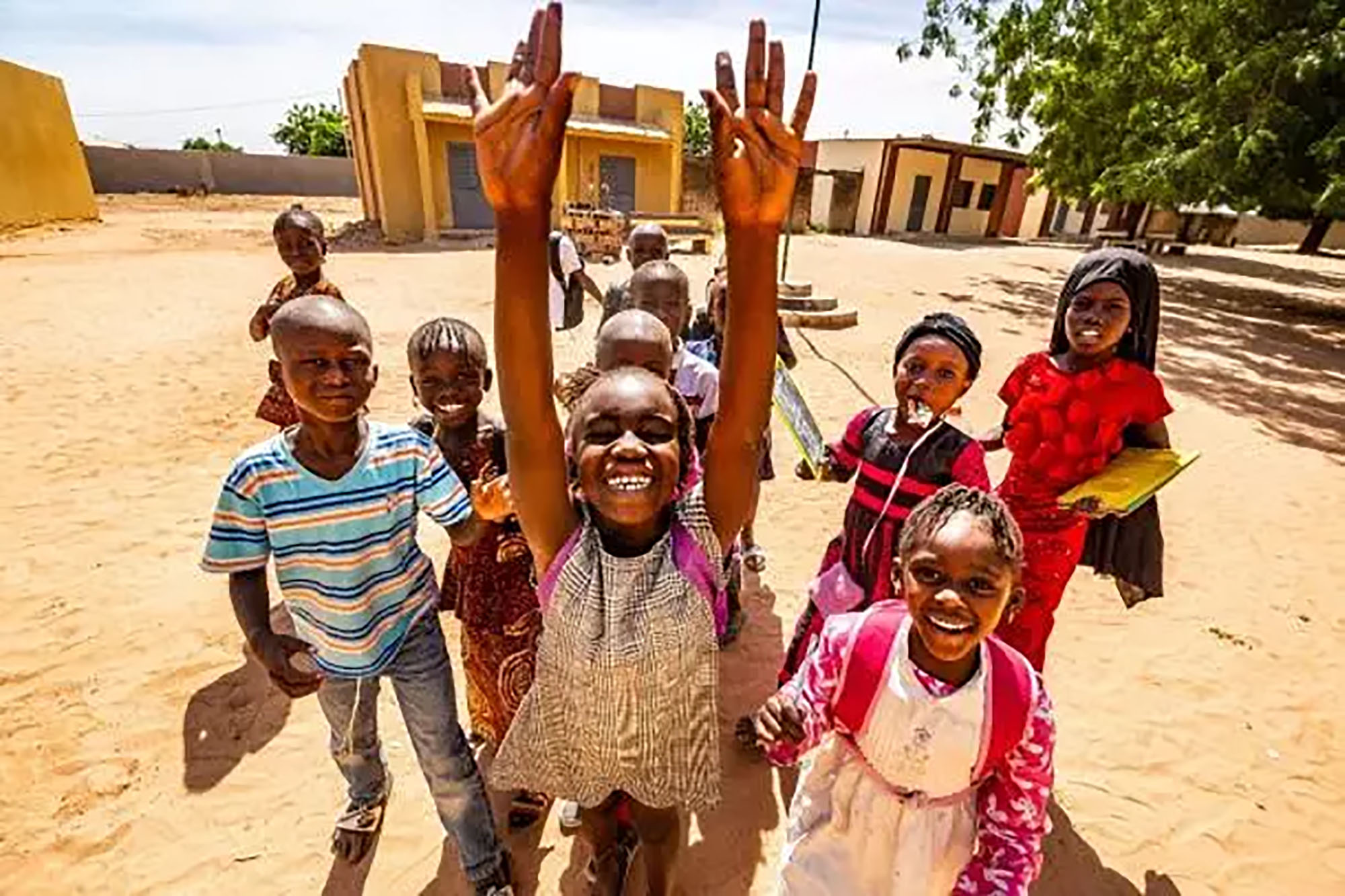 A group of African schoolchildren waving at the camera