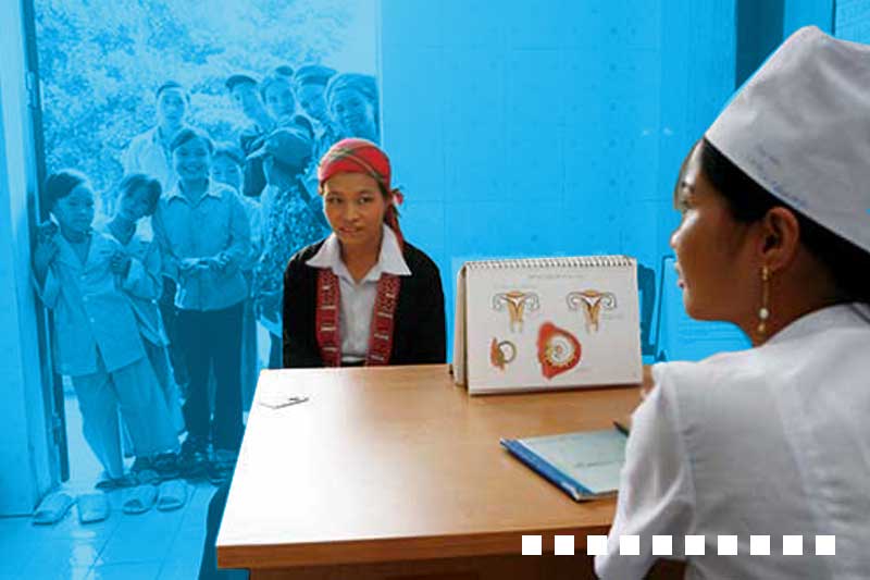 a nurse is seated opposite a young woman and a notebook illustrating female reproductive organs is on the desk
