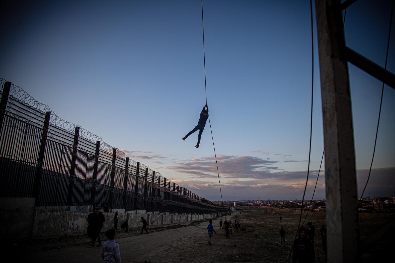child hanging off electrical wire as other children look on