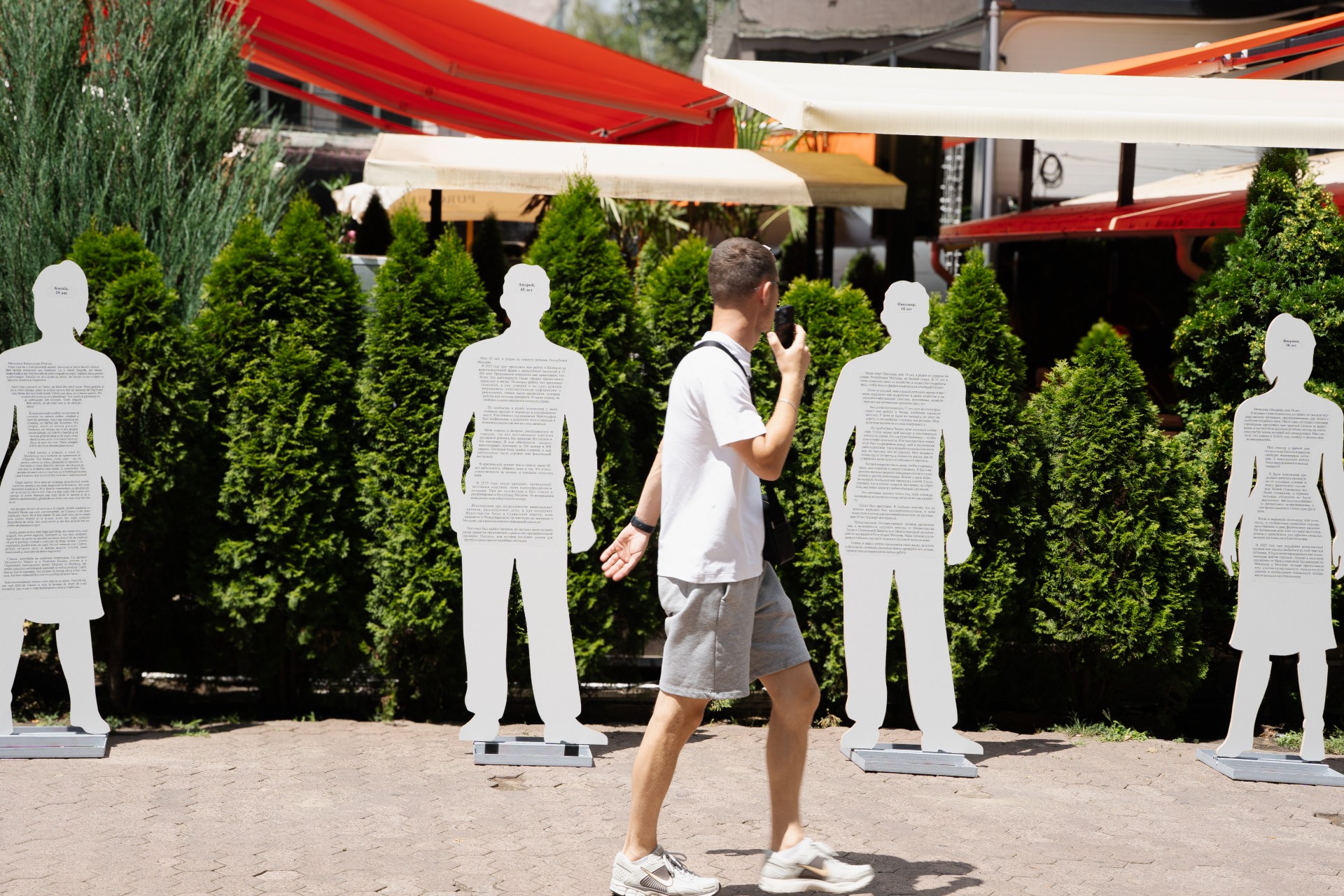 A man walking past artwork depicting human stories.