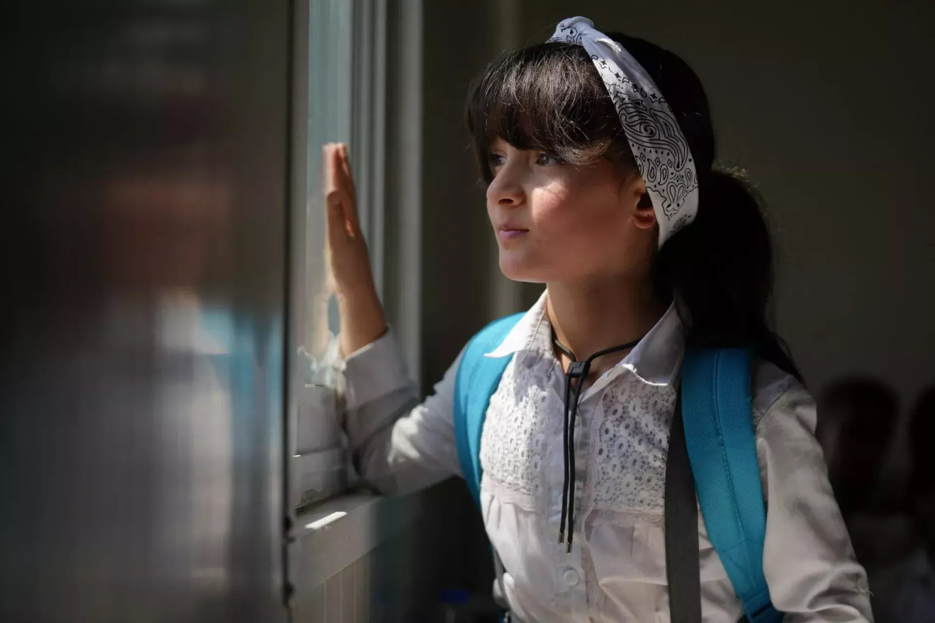 A young girl staring outside the window.