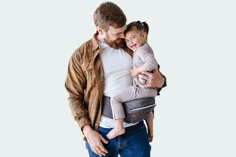 A man carrying his daughter on a baby carrier fashioned with a seat. 