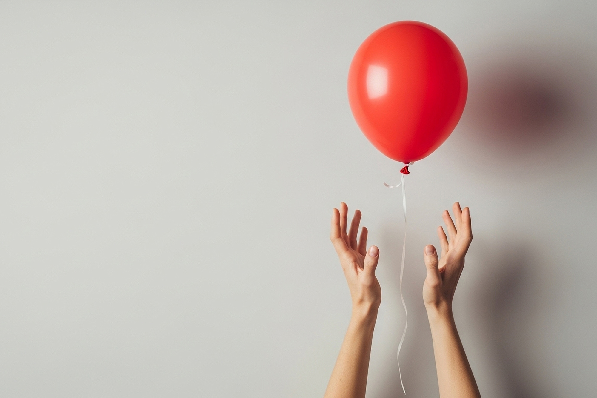 Red balloon floating above hands, symbolizing hope and freedom for World Duchenne Awareness Day.